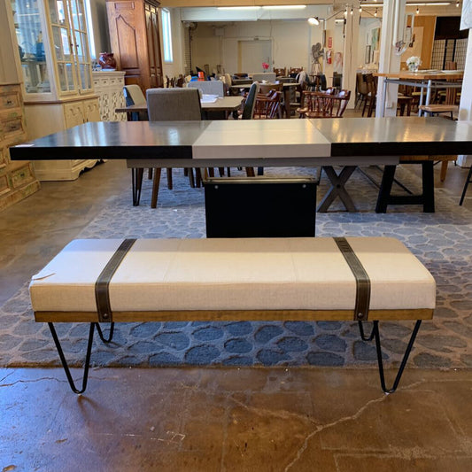 Beige bench with black straps in a room with tables and chairs