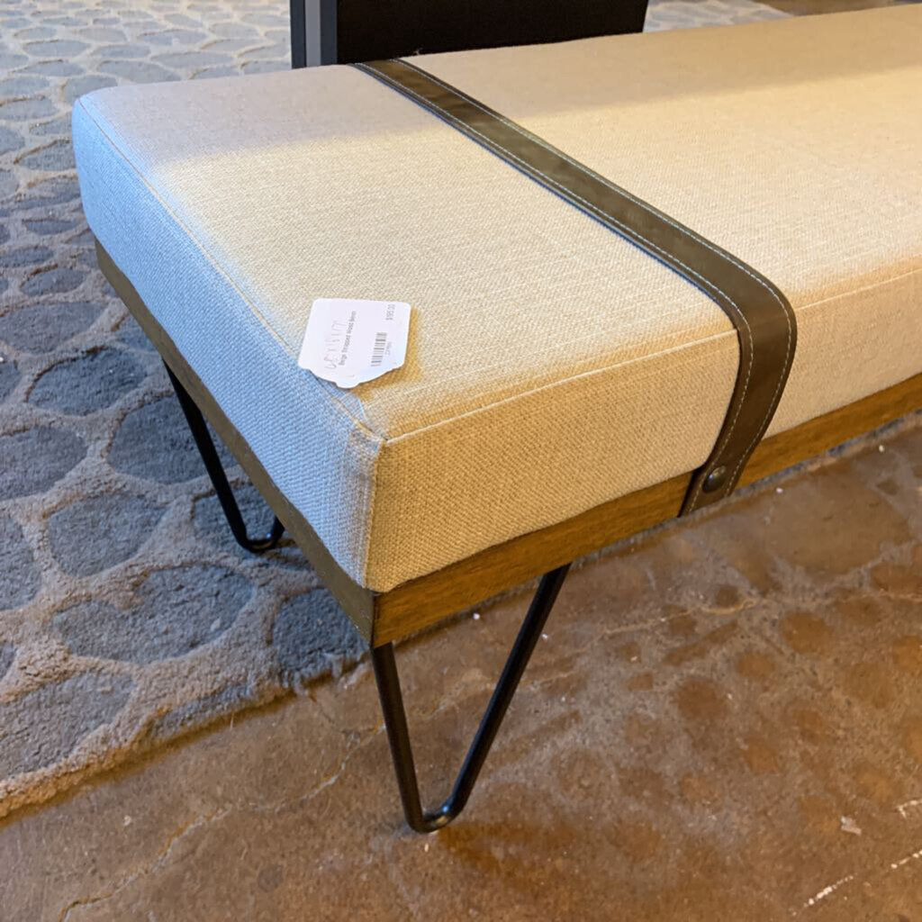 Beige and blue cushioned bench with a price tag on a stone pavement.