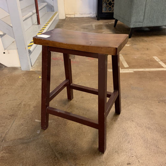 Wooden bar stool on a concrete floor with a blurred background