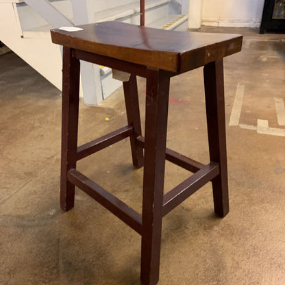 Wooden bar stool on a concrete floor with a blurred background