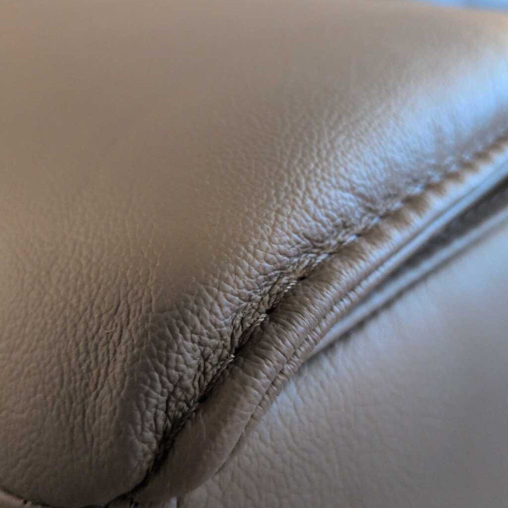 Close-up of a brown leather armrest with visible wear and tear.
