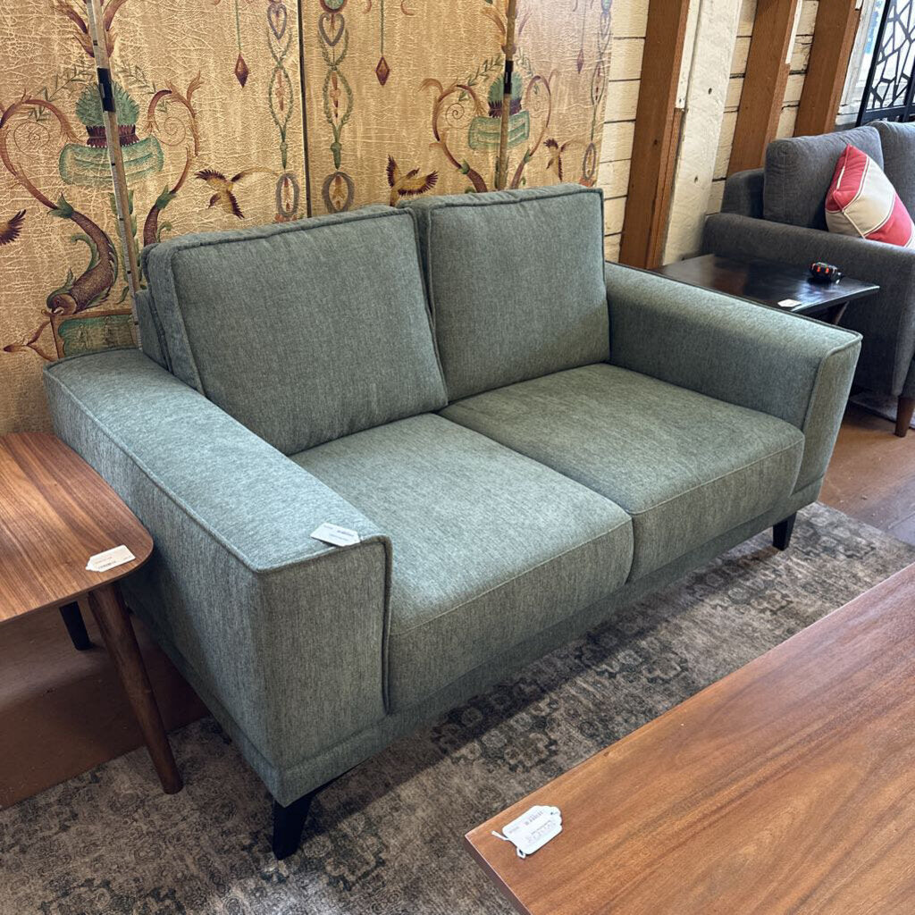 Gray sofa in a room with wooden tables and decorative wall art
