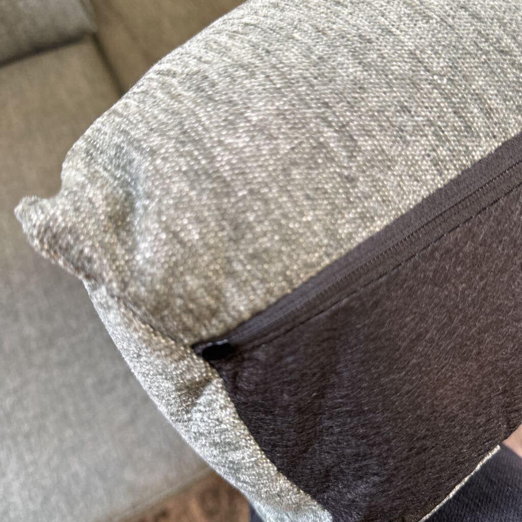 Close-up of a textured pillow with a zipper on a couch.