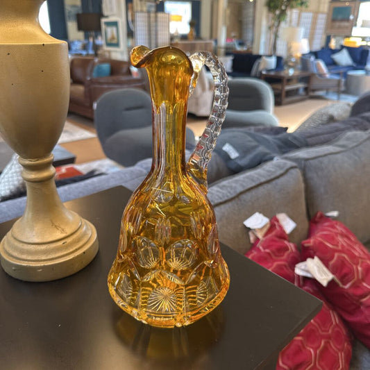 Decorative amber glass pitcher on a table with a blurred living room background