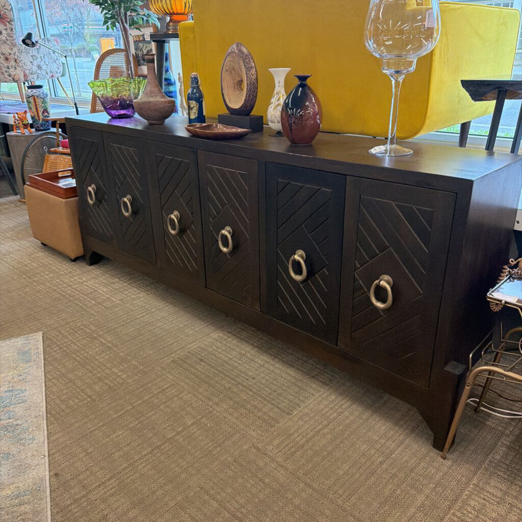 Dark wooden sideboard with decorative items in a room with yellow walls and a rug.