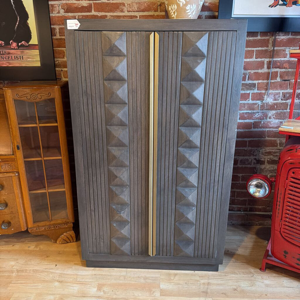 Wooden cabinet with geometric design in a room with brick wall and wooden floor.