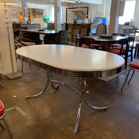 Vintage-style dining table with chrome legs in a showroom setting