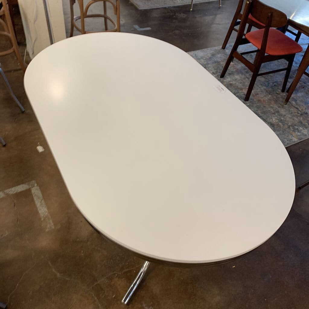 White oval table with a metal leg in an indoor setting