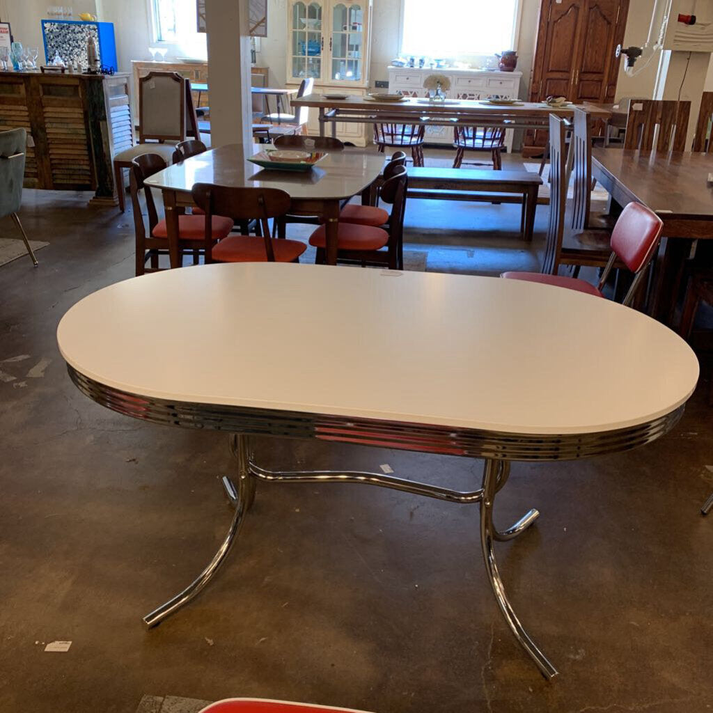 Vintage-style dining table with chrome legs in a room with chairs and tables.