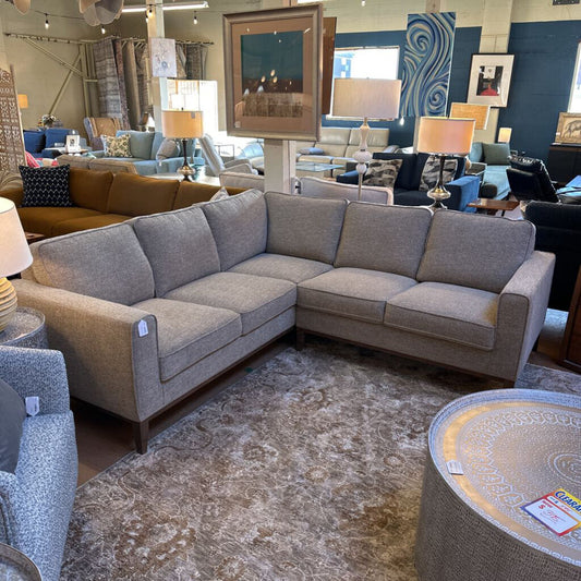 Gray sectional sofa in a showroom with various decor items.