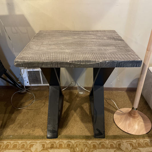 Small square table with textured surface and black legs in a room setting.