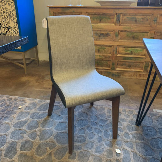 Chair with a textured backrest and wooden legs on a stone floor.