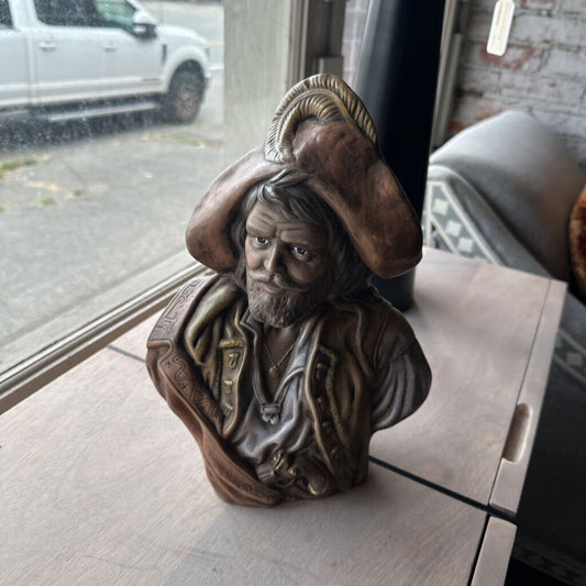 Bronze bust of a man with a hat on a window sill