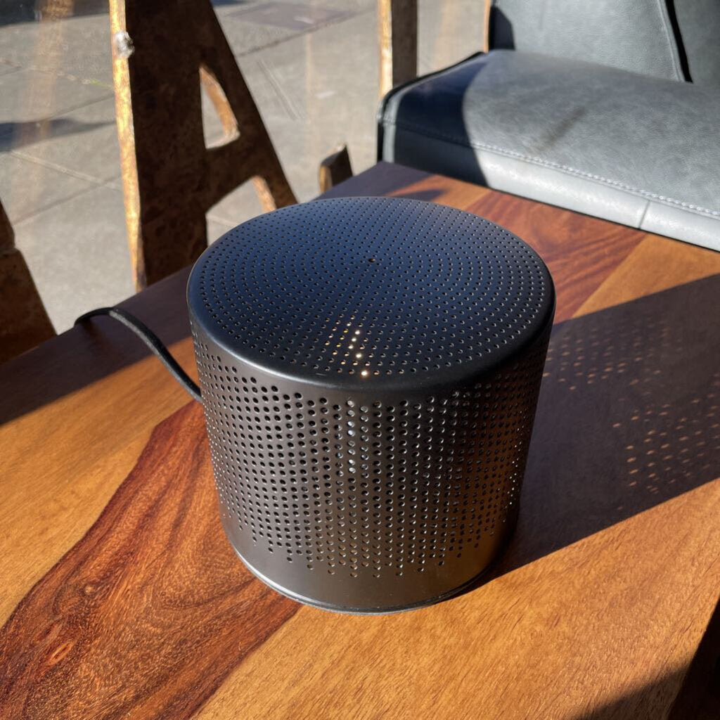 Black perforated cylindrical object on a wooden surface