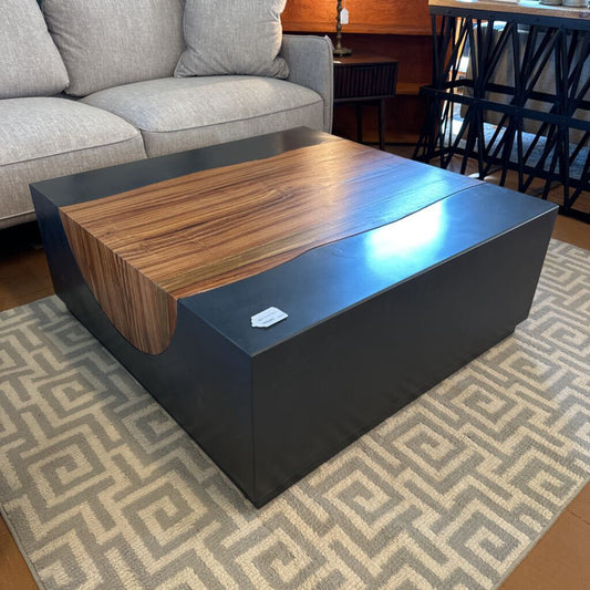 Modern coffee table with wooden top and black base in a living room setting