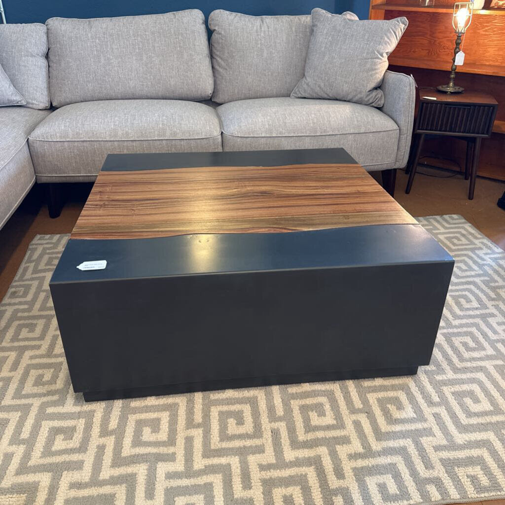 Gray sectional sofa with a wooden coffee table on a patterned rug.