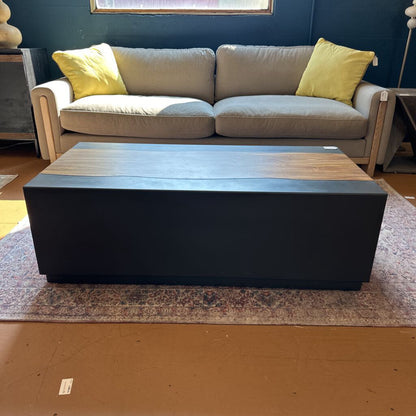 Gray sofa with yellow cushions and a black and wooden coffee table in a room.