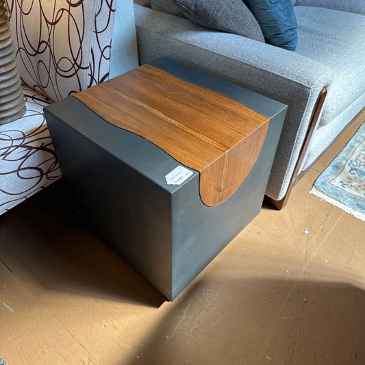 Small side table with wooden top and gray base in a living room setting