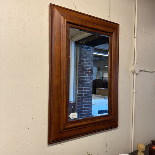 Wooden-framed mirror on a plain wall