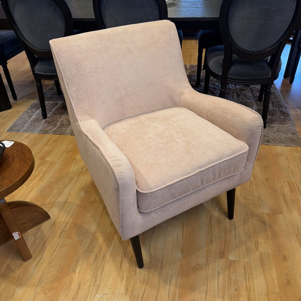 Beige armchair on a wooden floor with other furniture in the background