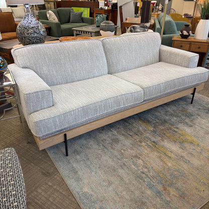 Gray and beige sofa in a showroom setting with other furniture.