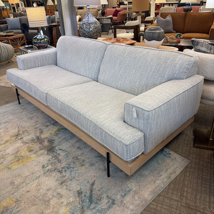 Gray sofa in a showroom setting with other furniture and decor items.