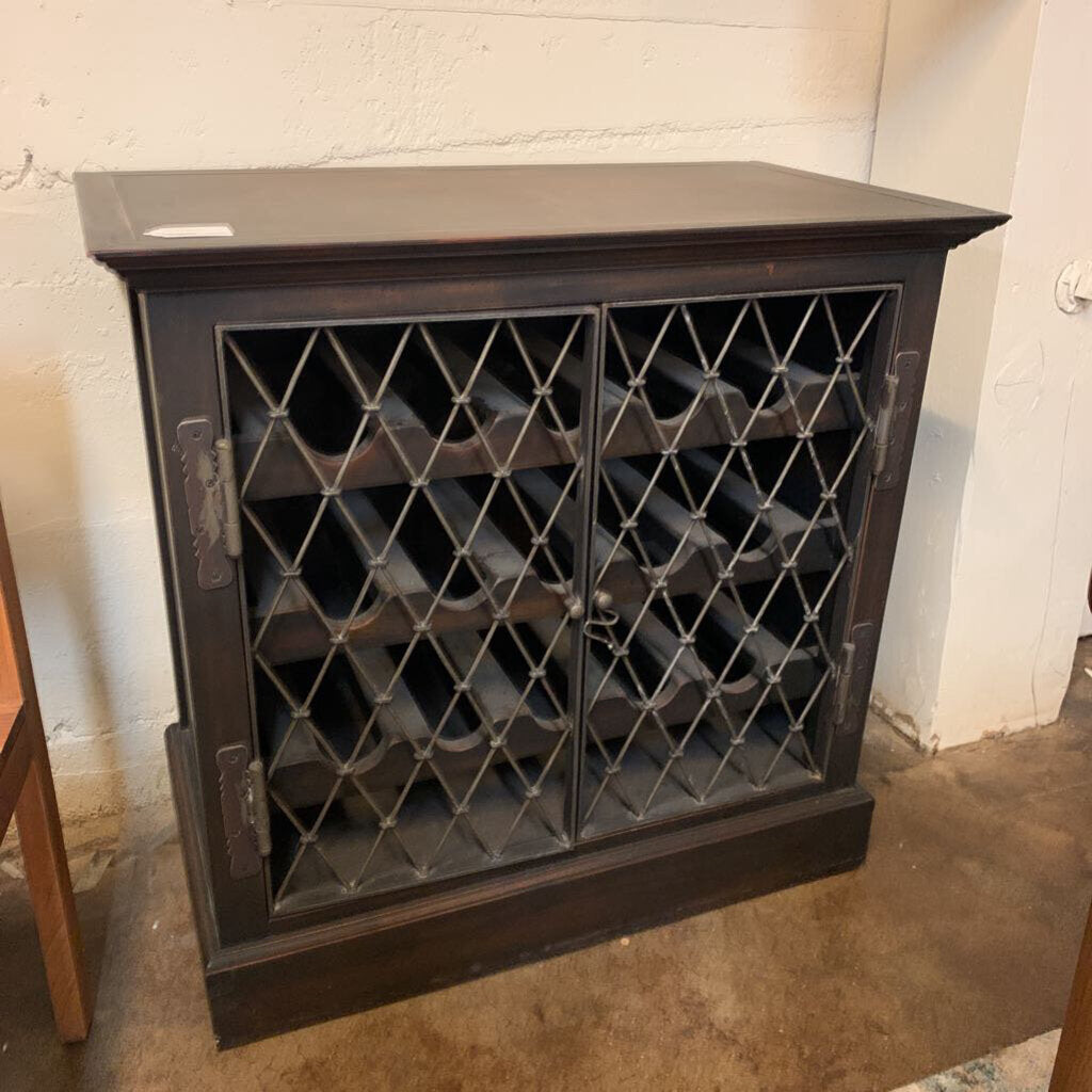 Dark wooden wine rack with lattice design doors against a white wall.