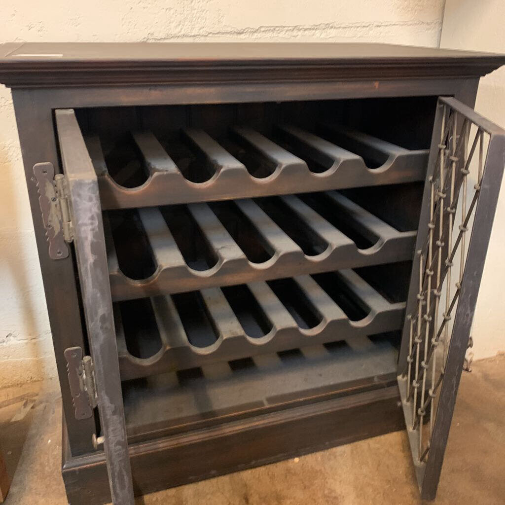 Wine rack with multiple bottles inside, placed against a textured wall.