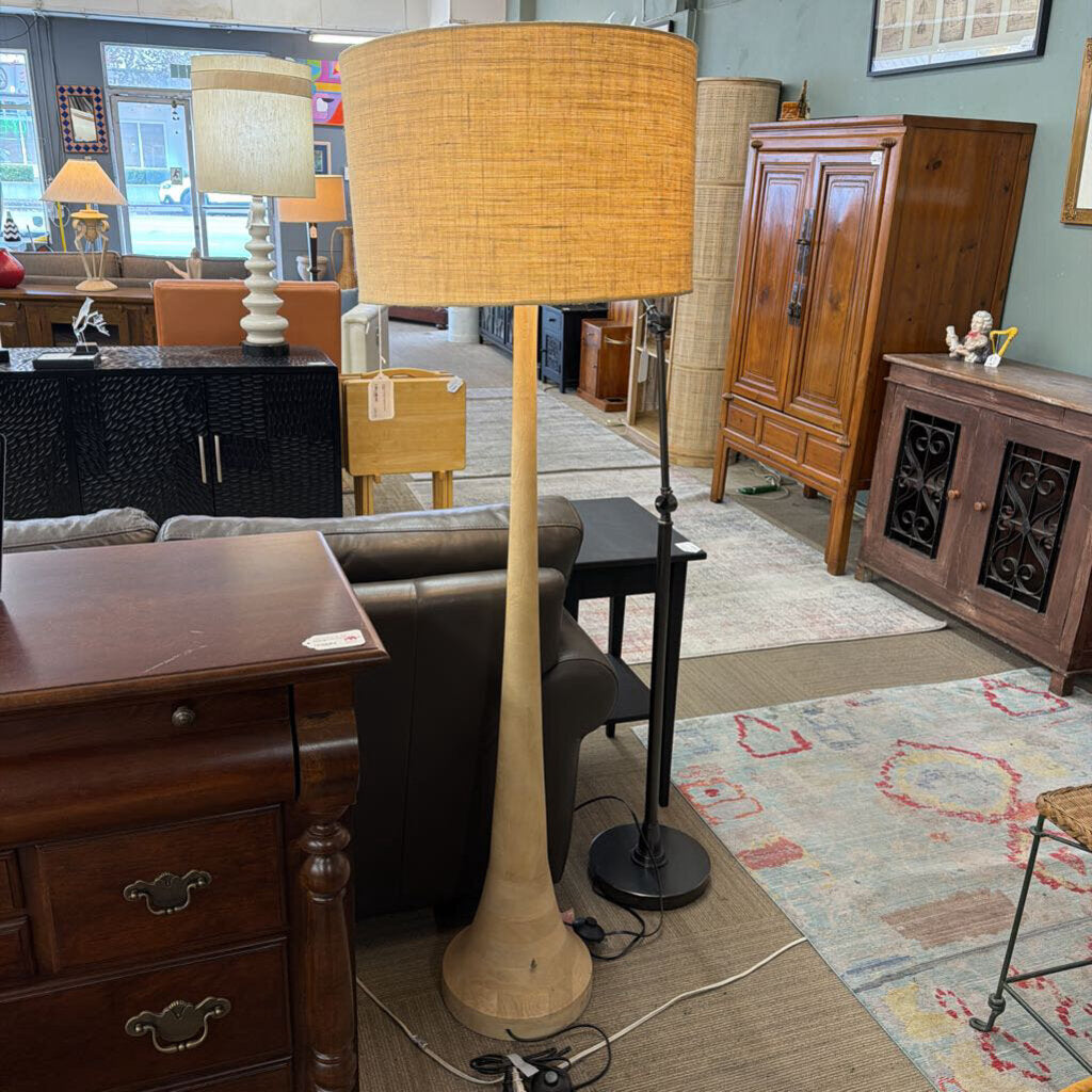Furniture store with various items including a tall floor lamp, wooden cabinet, and side table.