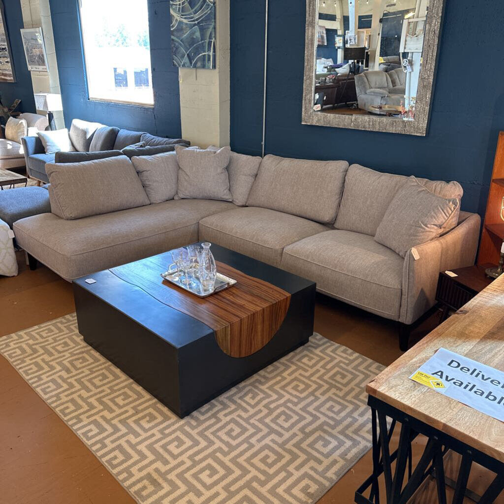 Beige sectional sofa in a living room setting with a coffee table and decorative items.
