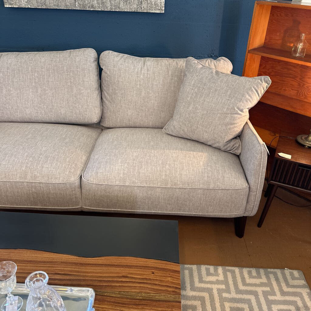 Gray sofa in a room with a wooden sideboard and decorative items.