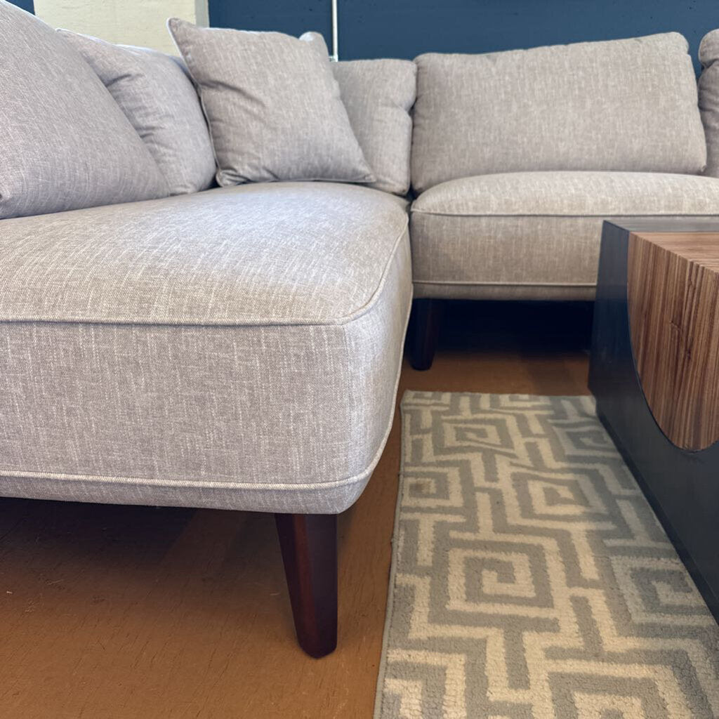 Gray sectional sofa in a room with a patterned rug and wooden coffee table.