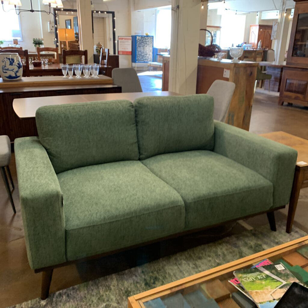 Green sofa in a showroom with furniture and decor around