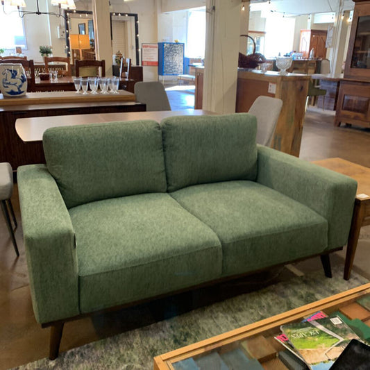 Green sofa in a showroom with furniture and decor around