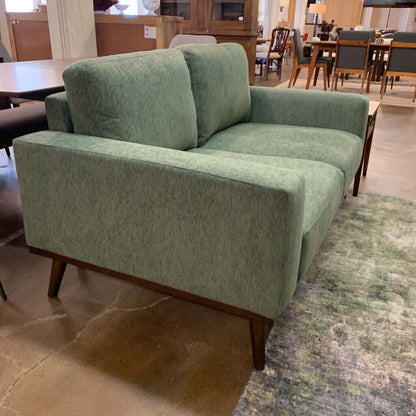 Green sofa in a room with tables and chairs