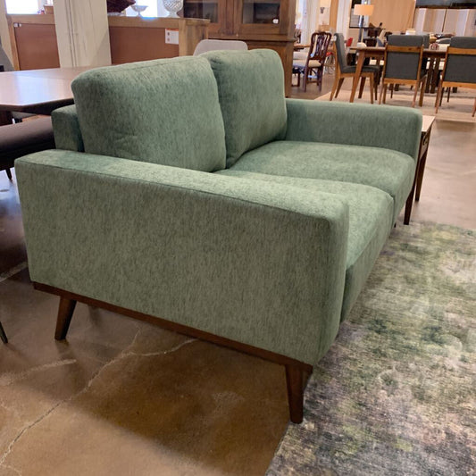Green sofa in a room with tables and chairs