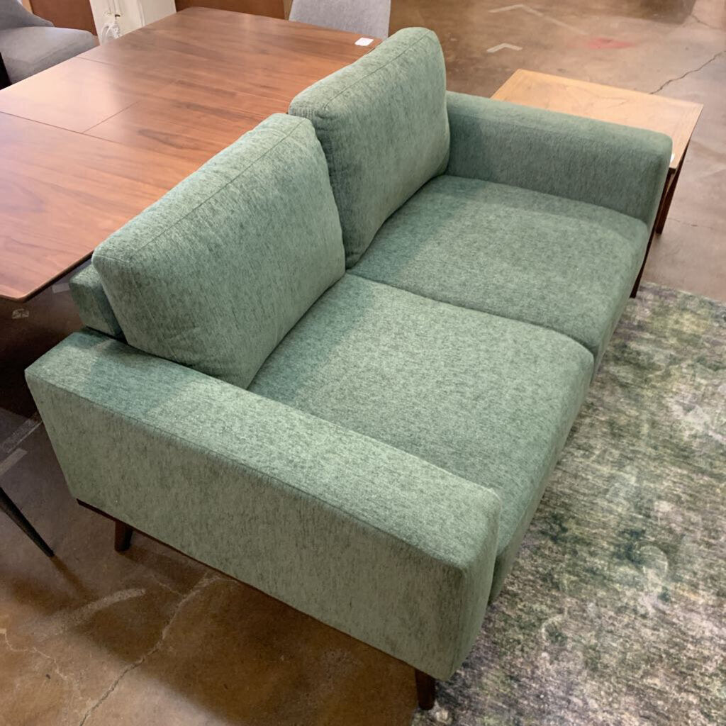 Green sofa in a room with a wooden table and rug.
