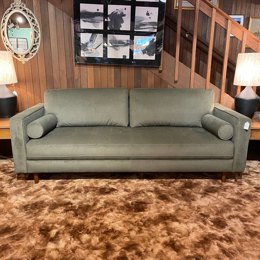 Gray sofa in a room with wooden walls and a staircase.