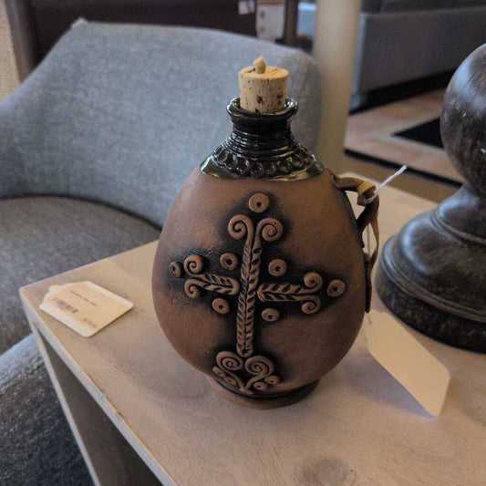 Decorative ceramic bottle with cross design on a table