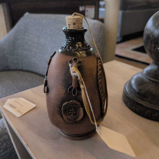 Decorative ceramic bottle with a tag on a wooden surface