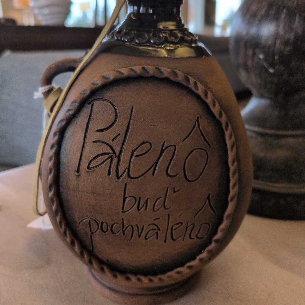 Bottle with 'Pálenó budň pochvaleno' engraving on a wooden surface
