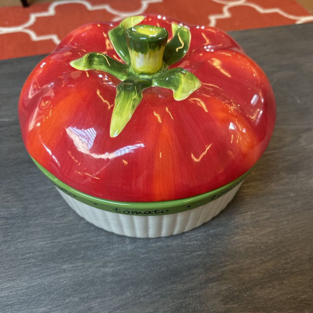 Ceramic tomato-shaped container on a gray surface