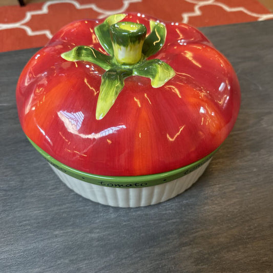 Ceramic tomato-shaped container on a gray surface