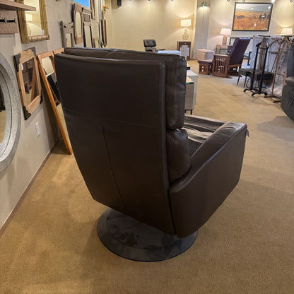 Black leather armchair in a showroom setting with mirrors and furniture on display.