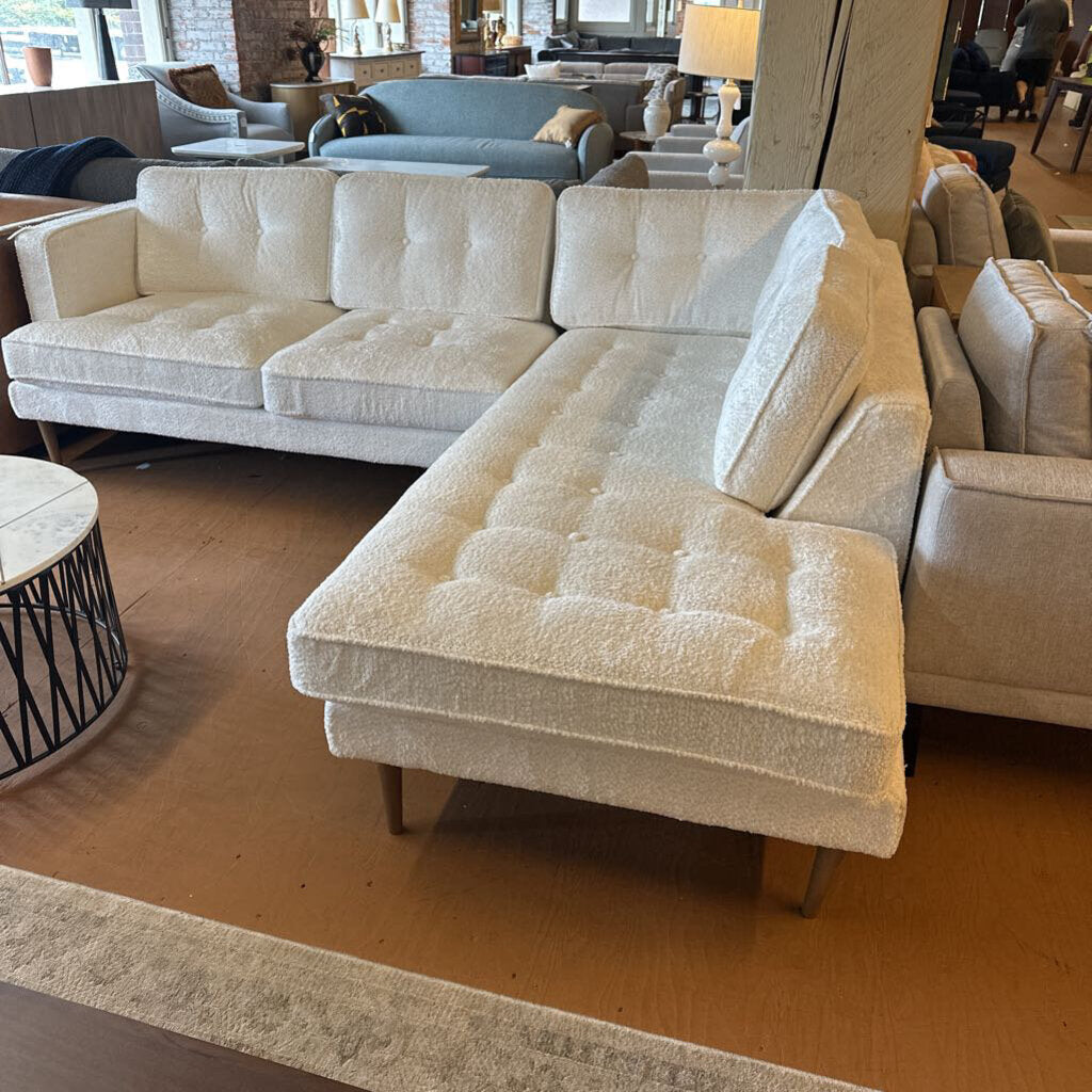 Beige sectional sofa in a showroom setting with other furniture.
