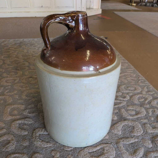 Ceramic jug with brown top and white base on a textured surface