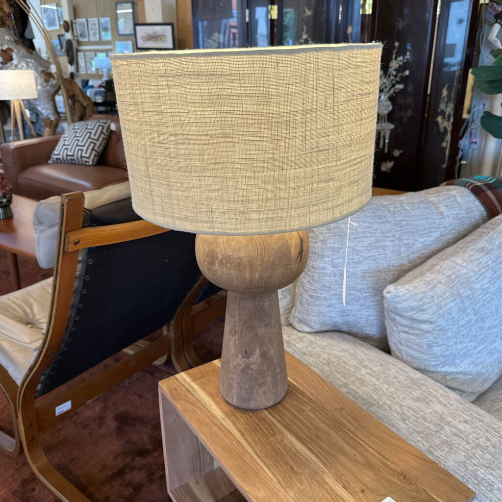 Table lamp with woven shade on a wooden table in a room setting