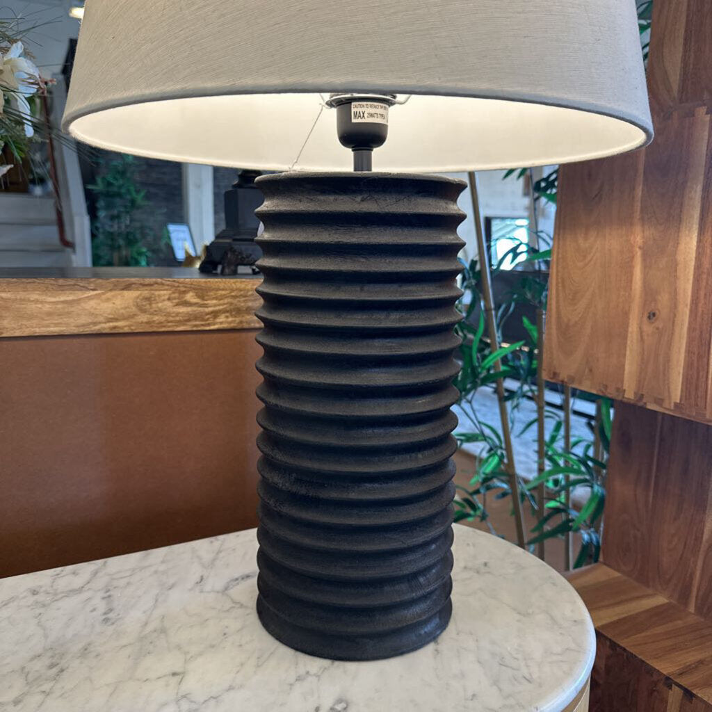 Table lamp with ribbed black base and gray shade on a marble surface.