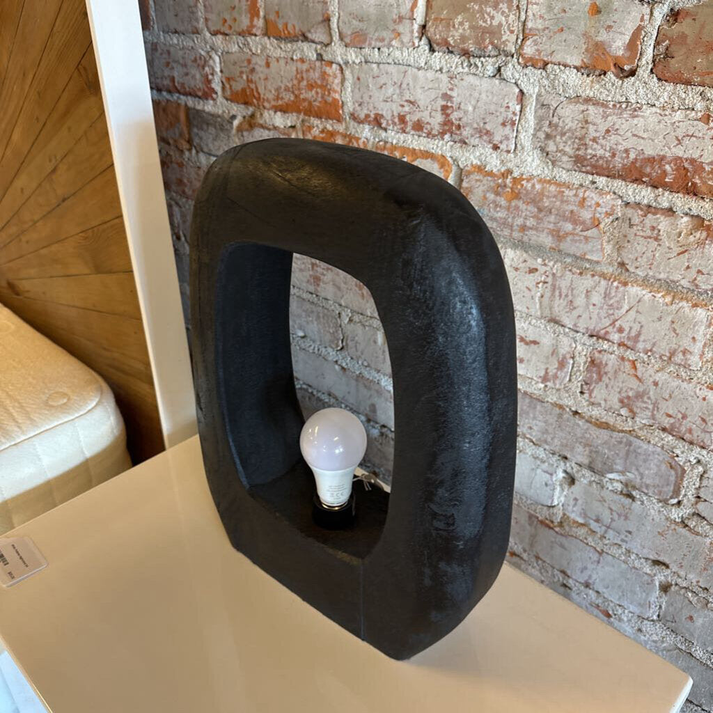 Black lamp with a light bulb inside against a brick wall