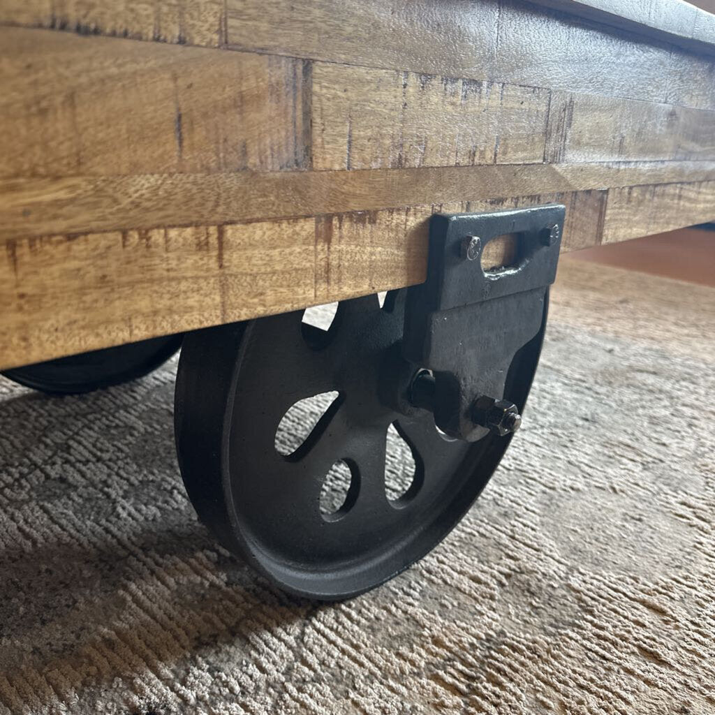 Wooden cart with a black wheel on a textured surface